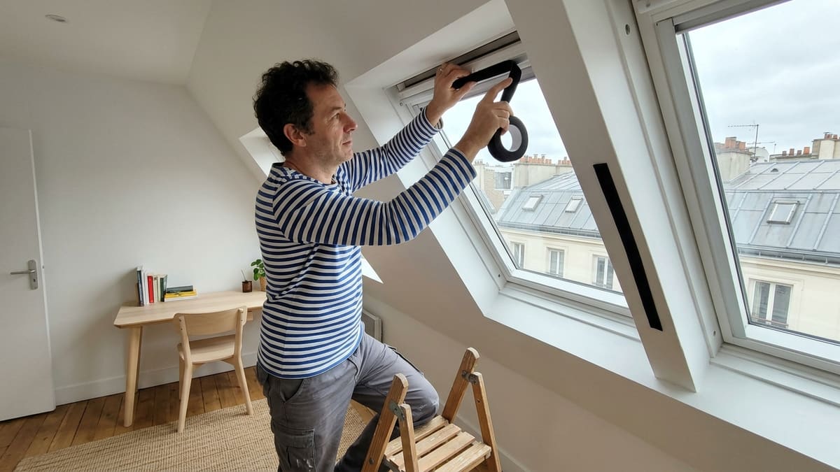 Locataire installant un tissu occultant velcro sur une fenêtre de toit Velux sans perçage